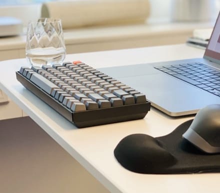 glass and keyboard near a laptop on a desk