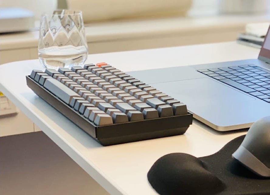 glass and keyboard near a laptop on a desk